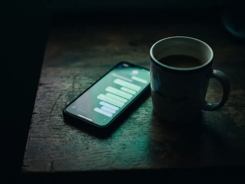 A phone on a dark desk showing a long stream of chat messages
